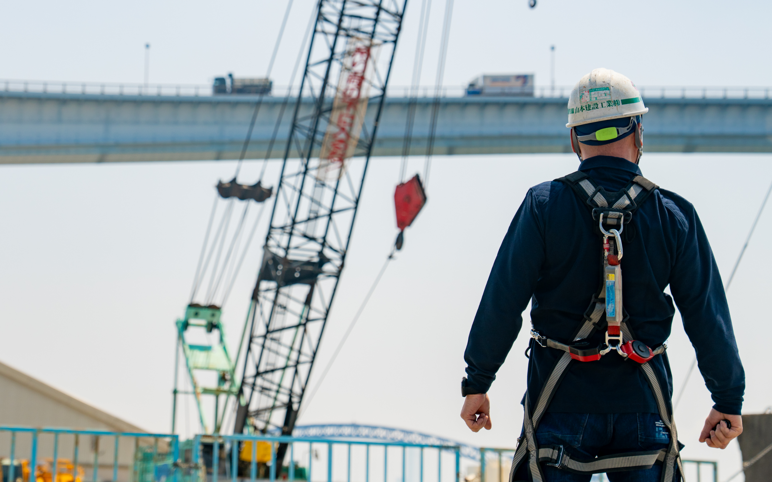 工事中の橋を眺める男性の後ろ姿